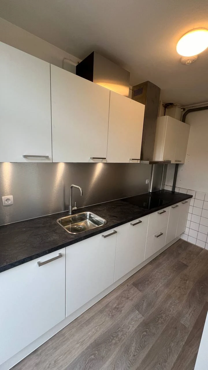 Geplaatste witte keuken met spoelbak, kookplaat en ingebouwde afzuigkap in Groningen