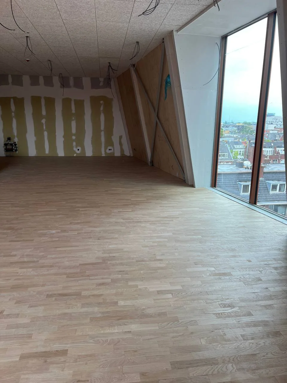 Op maat afgewerkte houten wand naast een groot raam bij VRIJDAG Groningen